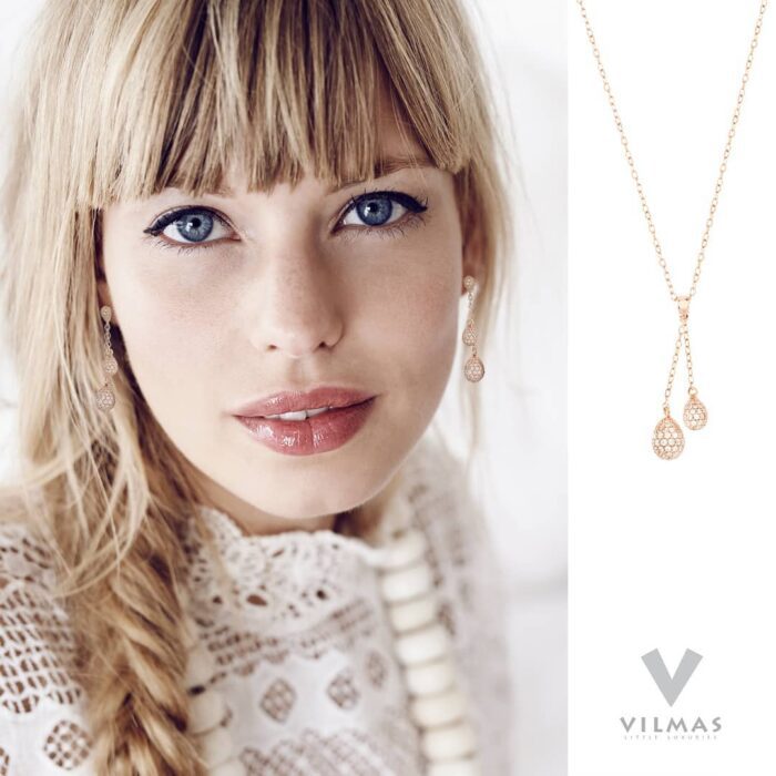 Portrait einer jungen Frau mit geflochtenem Zopf, romantischer Spitzenbluse und OHrringen in gold